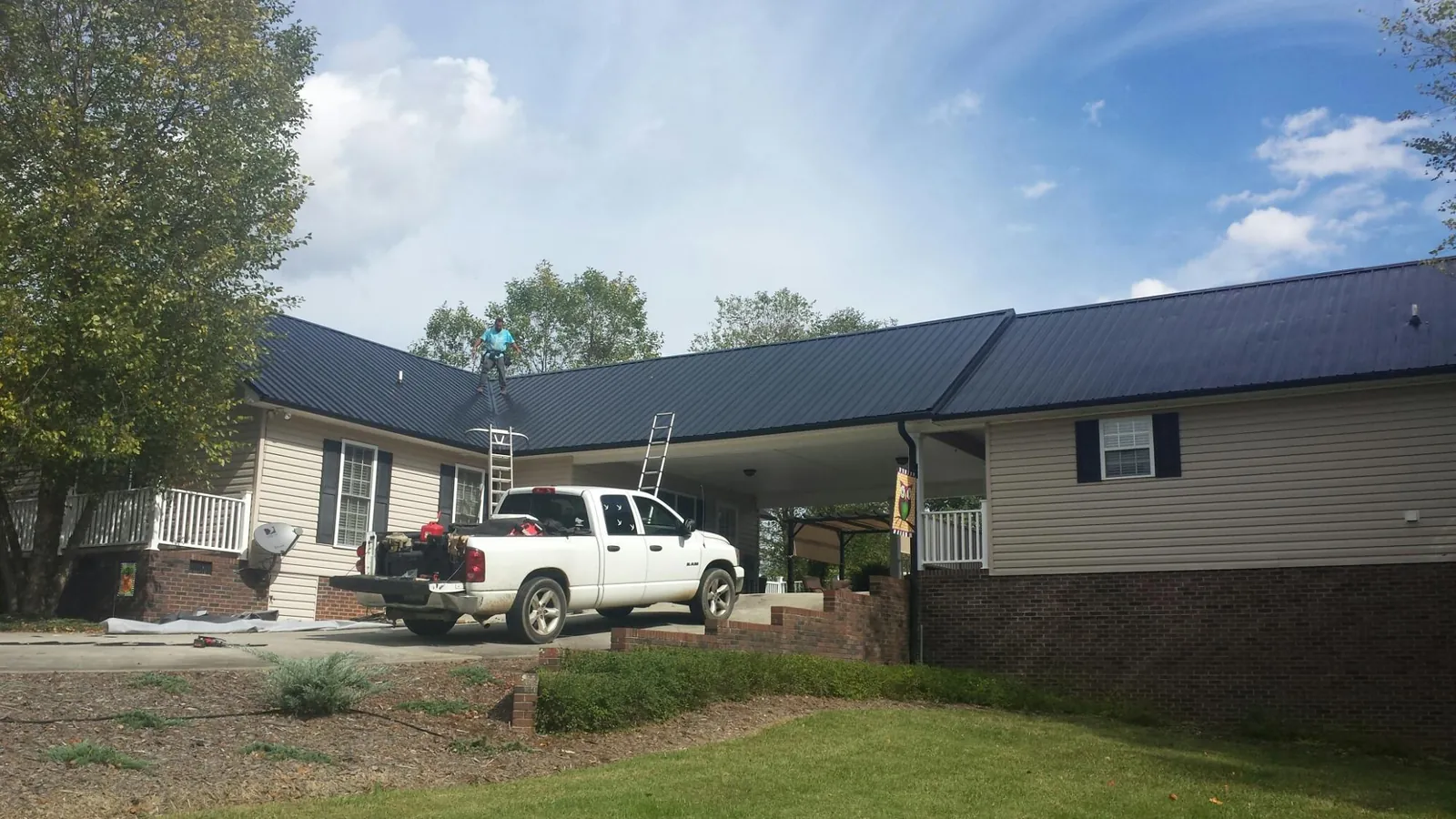 Black metal roof over a home and attached breezeway with ladders set in Plainfield